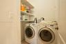 Utility area featuring white front-load laundry appliances and installed metal wire shelving