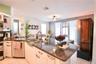 Kitchen featuring a peninsula with stone-finish countertops, stainless steel undermount sink, built-in stainless steel dishwasher, and white cabinetry