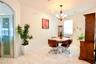 Light-filled room featuring large-format tile flooring, a multi-arm decorative chandelier, arched architectural detailing, and a door with frosted gla