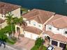 Two-story residence featuring a concrete tile roof, stucco exterior, paved driveway, two-car garage, and waterfront location