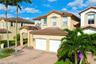 Stucco exterior residence featuring a tiled roof, paver driveway, two-car garage, and arched entryway