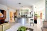 Curved kitchen island featuring a dark stone countertop and stainless steel facade, light-toned tile flooring, recessed ceiling lighting, and white ca