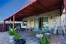 Covered outdoor patio featuring paver flooring, a retractable fabric awning, dual ceiling fans, and wall-mounted exterior light fixtures
