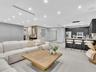 Open-concept interior featuring recessed ceiling lighting, matte black flat-panel cabinetry, a stone-topped kitchen island, neutral large-format floor