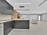 Contemporary kitchen featuring flat-panel charcoal cabinetry, light-toned stone countertops, linear pendant lighting, wood-slat accent wall detailing,