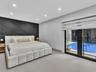 Geometric black wall paneling, recessed lighting, large-format tile flooring, and dual glass pane doors opening to an outdoor pool