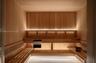 Sauna featuring custom wood wall paneling, tiered wood bench seating, and integrated linear lighting