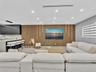 Slatted wood-finish feature wall with integrated vertical lighting, recessed ceiling lighting, linear kitchen island with stone-finish countertop, mat