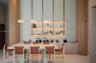 Floor-to-ceiling fluted wood columns, custom wall-mounted open shelving with integrated lighting, minimalist pendant lighting, and sleek custom cabine