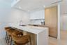 Kitchen featuring waterfall-edge stone countertops, custom cabinetry with wood-finish paneling, integrated refrigerator, stone backsplash, and stainle