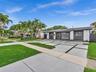 Single-story residence featuring a contrast-color exterior, grid-pattern concrete driveway, multi-pane windows, and mature palm trees