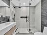 Bathroom featuring a floating vanity with integrated sink, walk-in shower with frameless glass enclosure, dual shower heads including a ceiling-mounte
