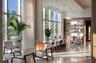 Floor-to-ceiling windows, high coffered ceiling with recessed lighting, polished stone flooring, and custom built-in wood shelving