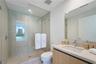Walk-in shower with floor-to-ceiling tile, frameless glass enclosure, wood-finish cabinetry, countertop vanity with integrated sink, and polished chro