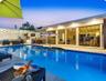 In-ground swimming pool with tile border, expansive covered patio, and floor-to-ceiling sliding glass doors