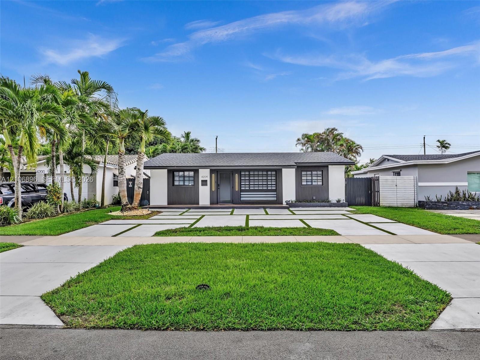 Exterior featuring a contemporary facade with a contrasting color palette, structured geometric paver driveway, manicured lawn, and mature palm trees