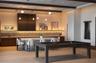 Custom cabinetry with integrated under-cabinet lighting, stone-surface kitchen island, wood-finish flooring, and decorative ceiling beams