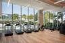 Fitness center featuring floor-to-ceiling windows, wood-finish flooring, linear suspended LED lighting, and recessed ceiling architecture