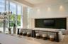 Floor-to-ceiling glass windows, recessed ceiling lighting, wood-finish flooring, integrated wall-paneling, and multi-light spherical chandelier