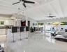 Open-concept interior featuring vaulted, beamed ceilings, oversized tile flooring, a kitchen island with stone countertops, and multiple sliding glass