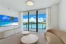Living area featuring floor-to-ceiling glass sliding doors, a private balcony with metal railing, and recessed ceiling lighting