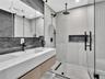 Floating vanity with an integrated sink and textured wood-finish cabinetry, paired with a frameless glass shower enclosure featuring matte black rainf