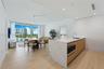 Kitchen island with stone-finish waterfall countertop, wood-finish cabinetry, recessed lighting, wood-finish flooring, and floor-to-ceiling glass slid