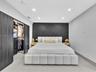 Interior room featuring a geometric paneled charcoal accent wall, recessed lighting, and large-format tile flooring