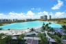 Expansive turquoise lagoon, white sand beach, paved walkways, mature palm trees, and structural shade cabanas