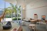 Floor-to-ceiling windows, high ceilings with sculptural pendant lighting, wood-paneled wall accents, and wall-to-wall carpeting