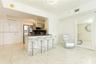 Kitchen area featuring a stone-topped breakfast bar, stainless steel refrigerator, dark cabinetry, recessed lighting, and polished stone-finish floori