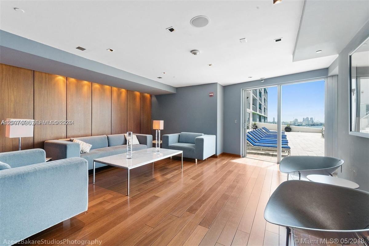 Wood-finish flooring, recessed ceiling lighting, full-height wood wall paneling, and glass sliding doors opening to an outdoor terrace