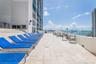 Expansive outdoor terrace featuring stone-tile flooring, glass panel railings, and tiered concrete steps