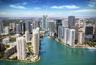 Aerial perspective of a high-density urban corridor featuring a central river, expansive waterfront exposure, glass-façade high-rise structures, and i