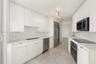 Kitchen featuring flat-panel white cabinetry, stone-surface countertops, full-suite stainless steel appliances, and stone tile flooring