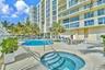 Outdoor terrace featuring a swimming pool, integrated spa, concrete deck surfacing, and mature palm trees