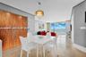 Textured wood-panel accent wall, pendant lighting fixture, and floor-to-ceiling glass paneling with water backdrop