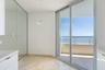 Floor-to-ceiling mirror paneling, stone flooring, minimalist pendant lighting, and full-height sliding glass doors opening to a balcony with water exp