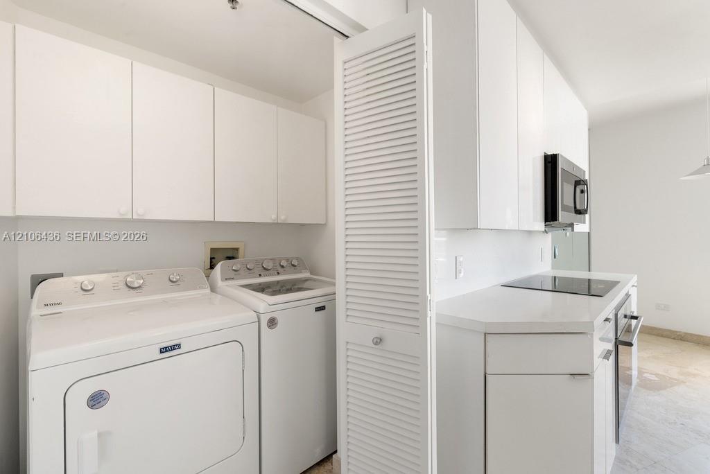 Laundry area featuring white cabinetry, louvered closet doors, and hard-surface countertops