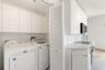 Laundry area featuring white cabinetry, louvered closet doors, and hard-surface countertops