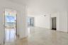Open interior featuring polished stone flooring, crown molding, floor-to-ceiling glass sliding doors, and private balcony access