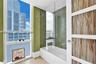 Bathroom featuring a glass-enclosed soaking tub, decorative mosaic tile surround, floor-to-ceiling windows, and a multi-panel door with integrated bot