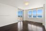 Dark wood-finish flooring, floor-to-ceiling windows, sliding glass door, recessed ceiling lighting, and covered balcony