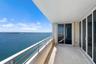 Covered balcony featuring stone tile flooring, a horizontal metal railing, and sliding glass door entry