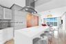 Kitchen featuring a central island with a solid-surface countertop, stainless steel overhead range hood, white cabinetry, wood-finish paneling, and po