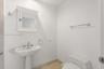 Pedestal sink with polished chrome fixtures, wall-mounted medicine cabinet with crown molding, and stone-finish flooring
