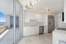 Kitchen featuring flat-panel white cabinetry, stone flooring, stainless steel appliances, and sliding glass doors opening to a balcony
