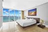 Floor-to-ceiling glass panel walls, light-toned stone flooring, and recessed ceiling lighting