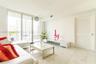 Living area featuring floor-to-ceiling glass sliding doors, stone-finish tile flooring, and a louvered interior door