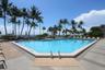 In-ground swimming pool featuring a concrete deck, metal pool ladders, and tropical palm tree landscaping